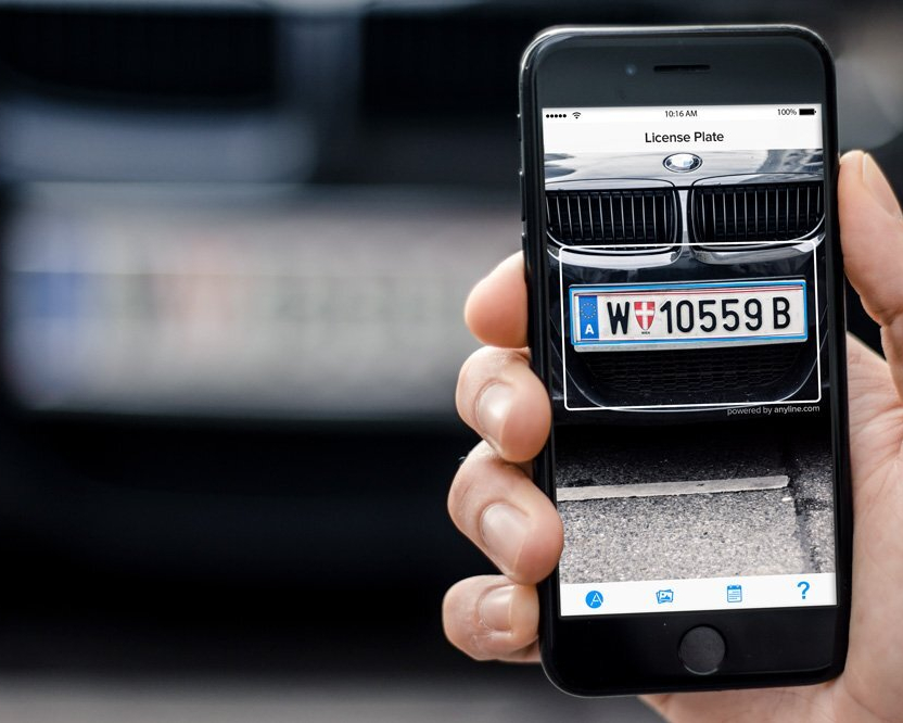 Man holding a phone that is scanning a license plate