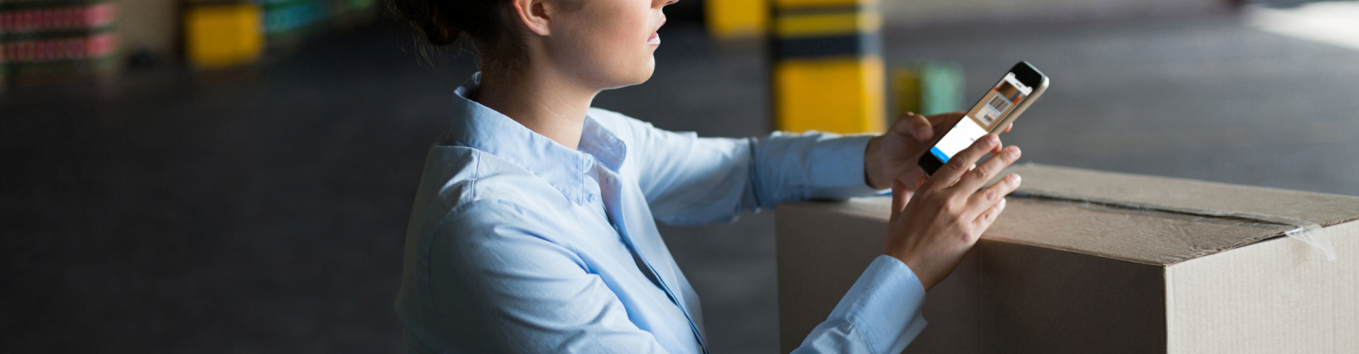Female factory worker using mobile phone with barcode scan